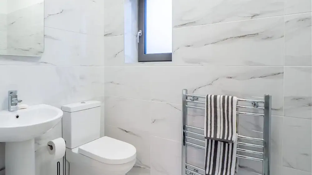 Bathroom in Oyster House, Ballinakill Bay. Bright coloured tiles with towels hanging on radiator. wp-image-583