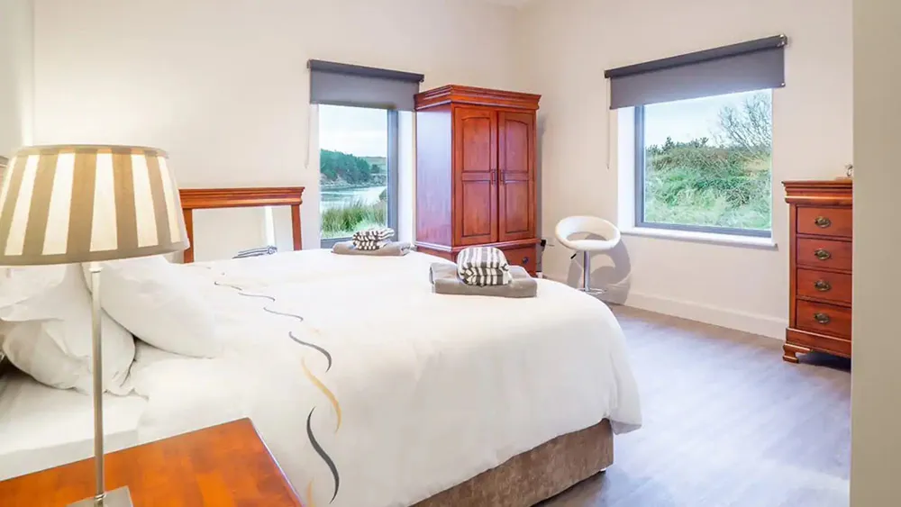 Oyster House Bedroom, with bright coloured bedsheets, bedside lamp and classic furniture. wp-image-589