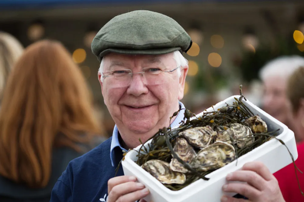 A Smiling David Keane of DK Connemara Oysters displaying a tray of oysters on his shoulder. wp-image-1395