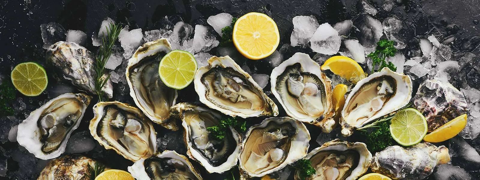 Selection of opened DK Connemara Oysters on ice, with sliced lemons and some green leafs