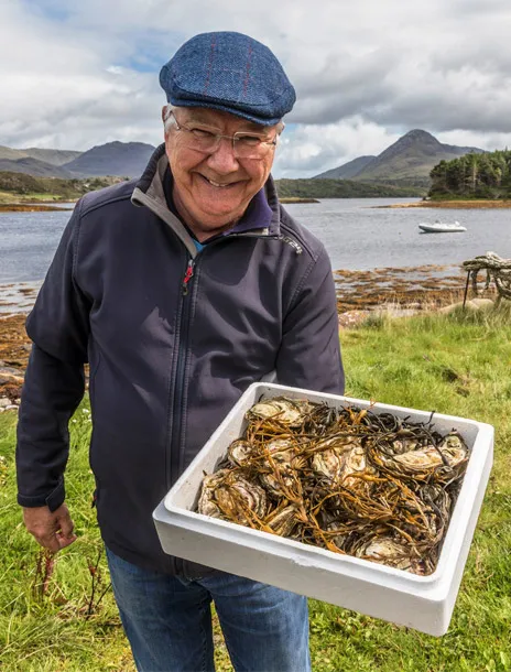 David from DK Connemara Oysters showing a platter of platter of fresh oysters beside the sea water.