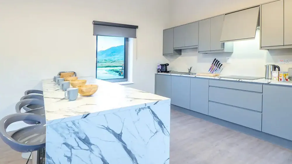 Oyster House kitchen, with marble island, grey cupboards and view of the bay through the window. wp-image-585