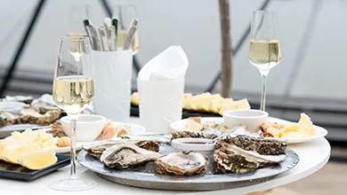 Platter of Oysters, lemons and glasses of Champagne on a table. wp-image-877