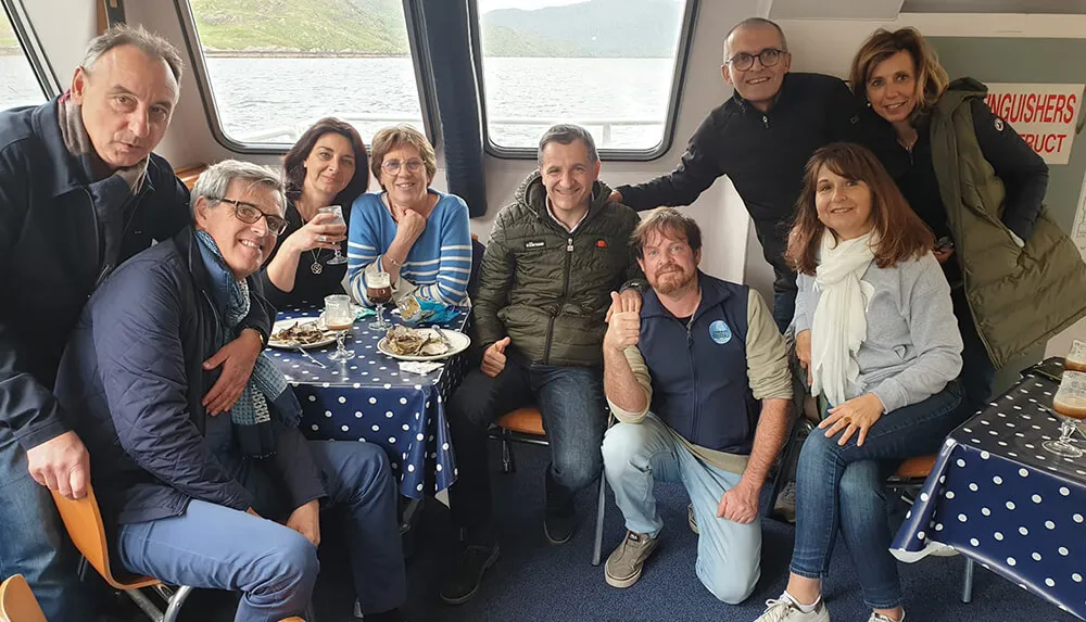 Tour group of nine on board a boat on Ballinakill Bay, Connemara with plates of oysters and drinks. wp-image-799
