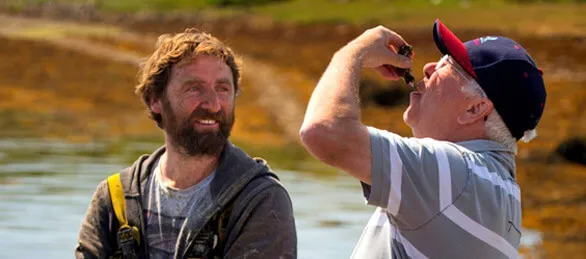 David Keane tastes a DK Connemara Oyster in the water of Ballinakill Bay. A staff member looks on.